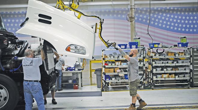 Workers lift a hood onto a chassis at a Mack Truck plant