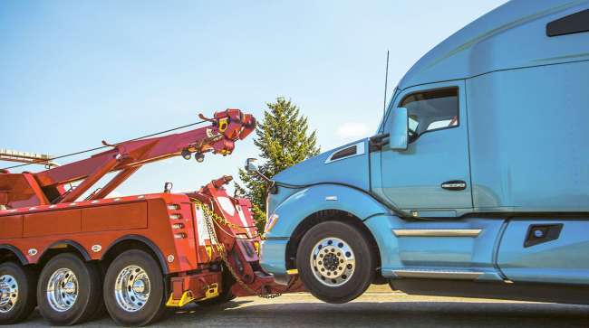 A tow truck hitches on to a tractor.